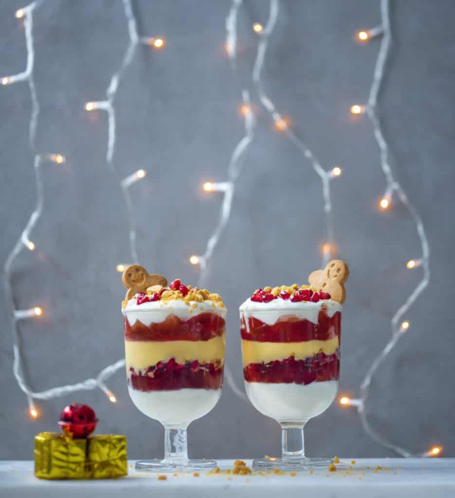 Healthy Christmas trifle with homemade custard and sugar- free jelly topped with pomegranates and crushed gingerbread men. Vegan and gluten-free too! #veganchristmas #vegantrifle #veganrecipes #veggiechristmas #veggierecipes #healthychristmas #christmastrifle #healthyrecipes