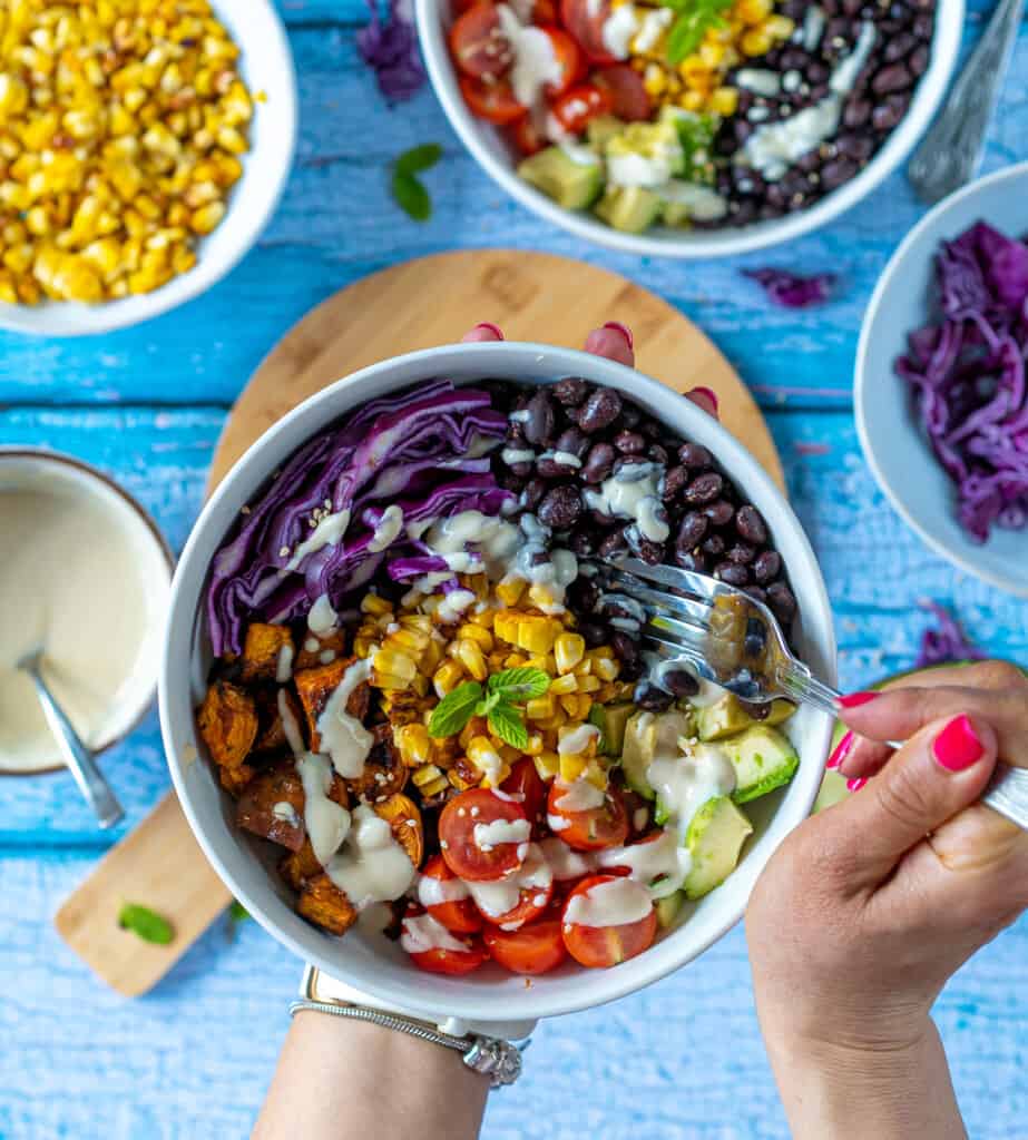 The best healthy Burrito Buddha Bowl packed with roasted sweet potatoes, smokey black beans, cherry tomatoes , creamy avocado and sweetcorn all drizzled with lush yoghurt and tahini dressing.